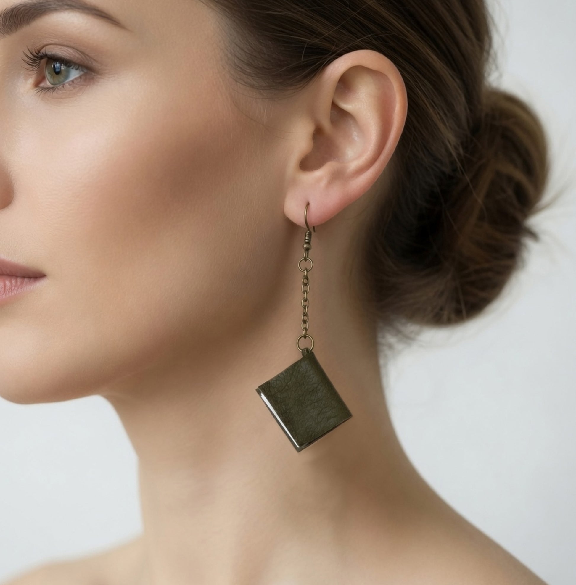 a small book-shaped earring in the ear