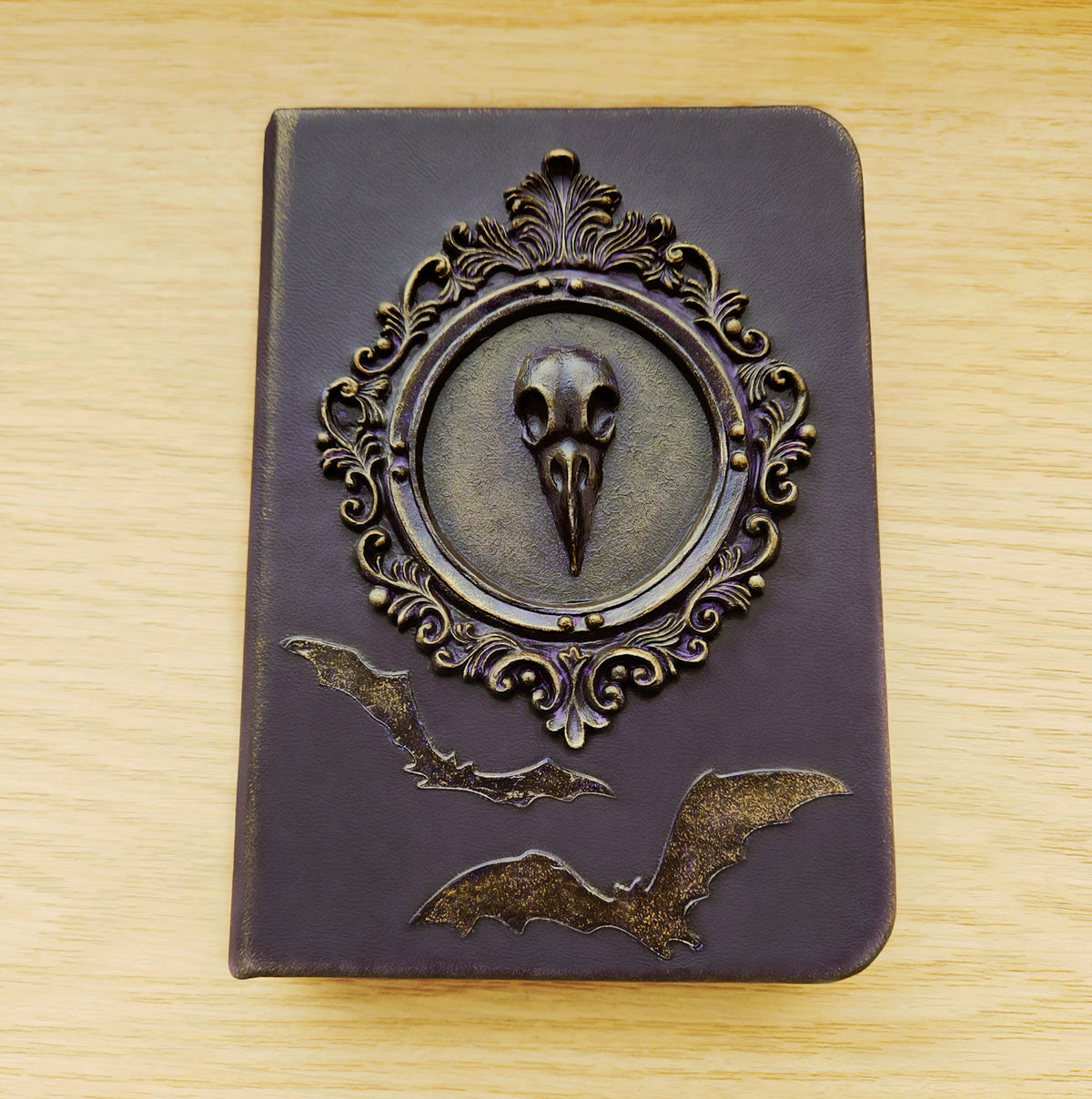 Purple leather notebook with a crow skull in a Victorian frame