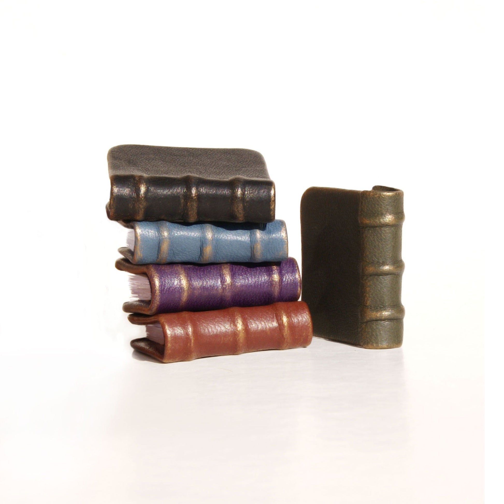 Stack of miniature books with different colored spines on a white background